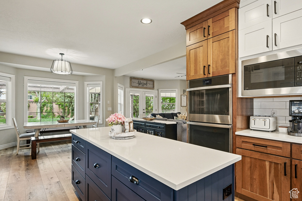 Kitchen featuring built in microwave, double oven, recessed lighting, plenty of natural light, and light countertops