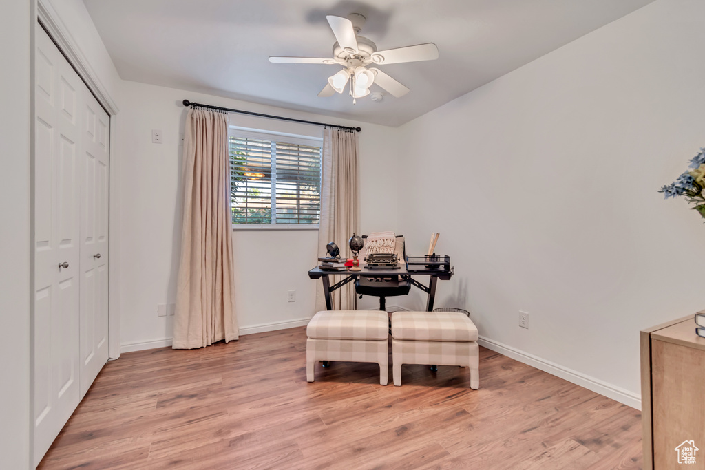 Office space with light wood-style floors, ceiling fan, and baseboards
