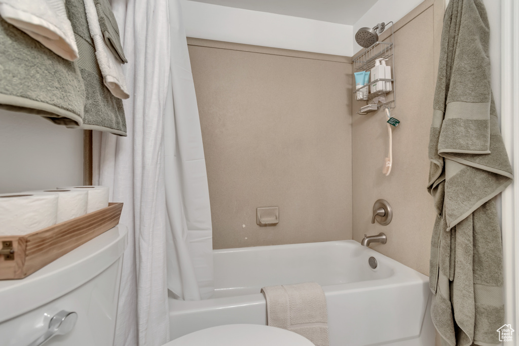 Bathroom featuring shower / bath combination with curtain and toilet