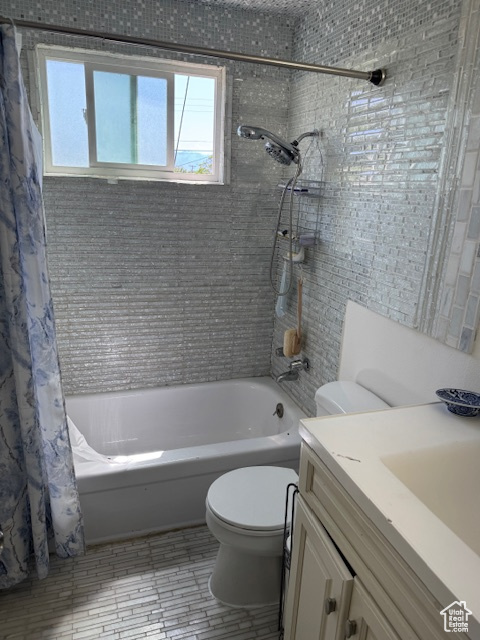 Bathroom featuring toilet, plenty of natural light, vanity, and shower / tub combo with curtain