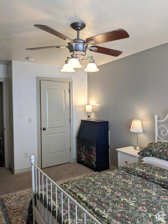 Bedroom featuring carpet, ceiling fan, baseboards, and a textured ceiling