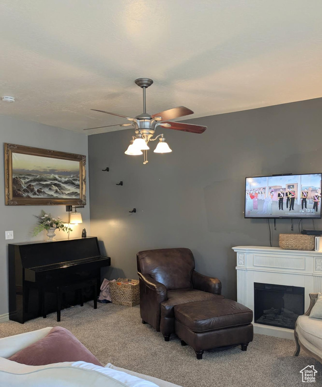 Living area featuring carpet floors, ceiling fan, and a glass covered fireplace