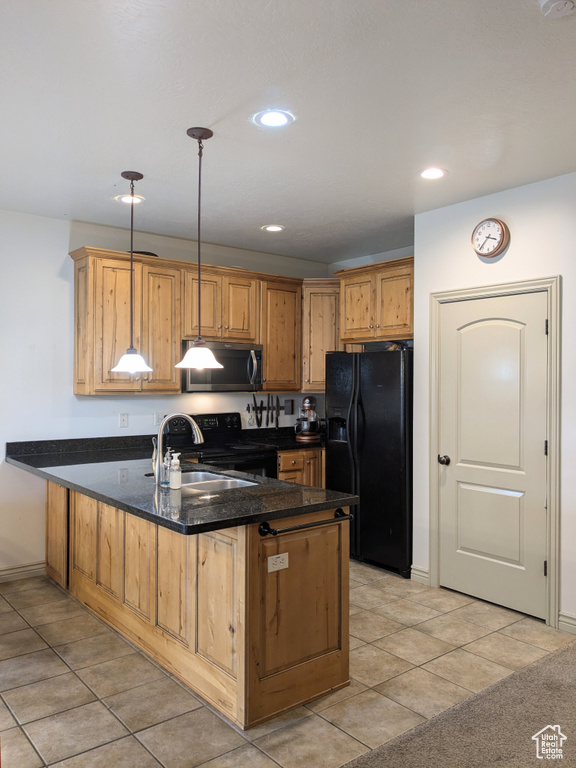 Kitchen featuring black refrigerator with ice dispenser, stainless steel microwave, a peninsula, a sink, and electric range oven