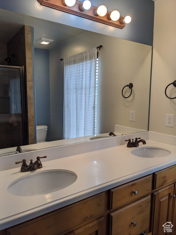 Full bath featuring double vanity, toilet, and a shower stall
