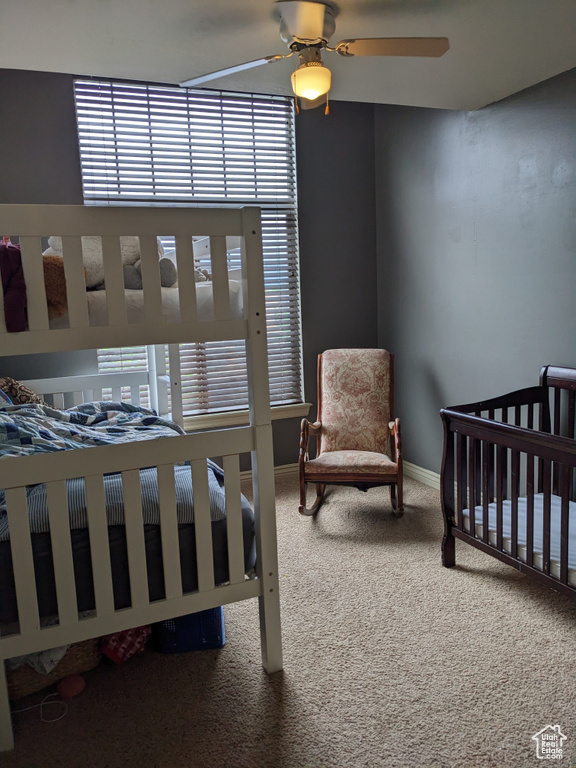 Bedroom featuring carpet, multiple windows, baseboards, and a ceiling fan
