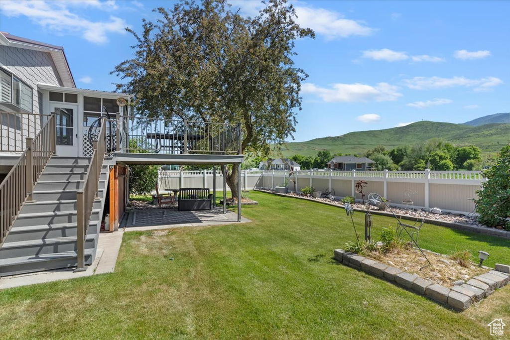 View of yard with a mountain view, a sunroom, stairs, and a patio area