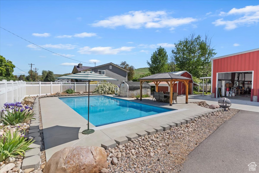 View of pool featuring a gazebo, a patio, a fenced backyard, and an outbuilding