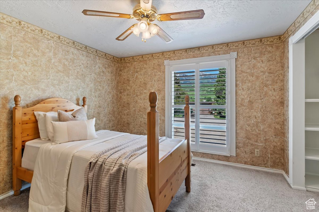 Bedroom with carpet, baseboards, a textured ceiling, and a ceiling fan