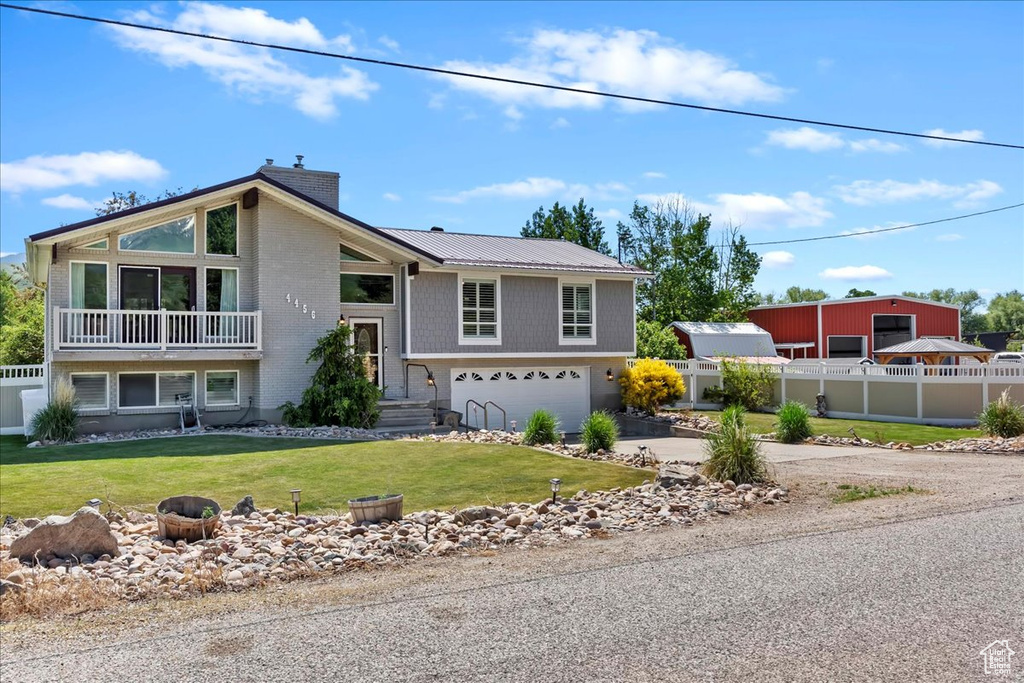 View of front facade featuring driveway, a garage, and metal roof