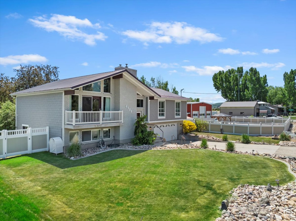 Back of property with an attached garage, a chimney, metal roof, and driveway