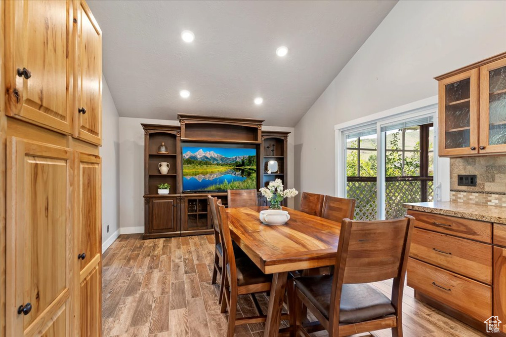 Dining area with lofted ceiling, light wood-style floors, and recessed lighting