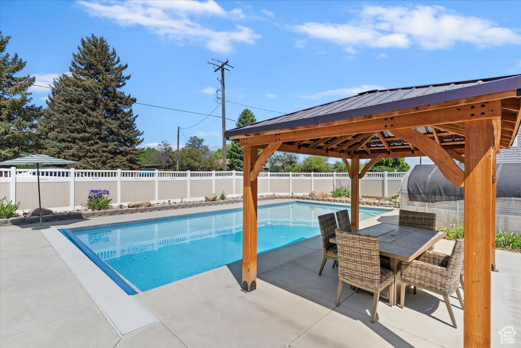 View of swimming pool with a gazebo, a patio area, a fenced backyard, and outdoor dining space