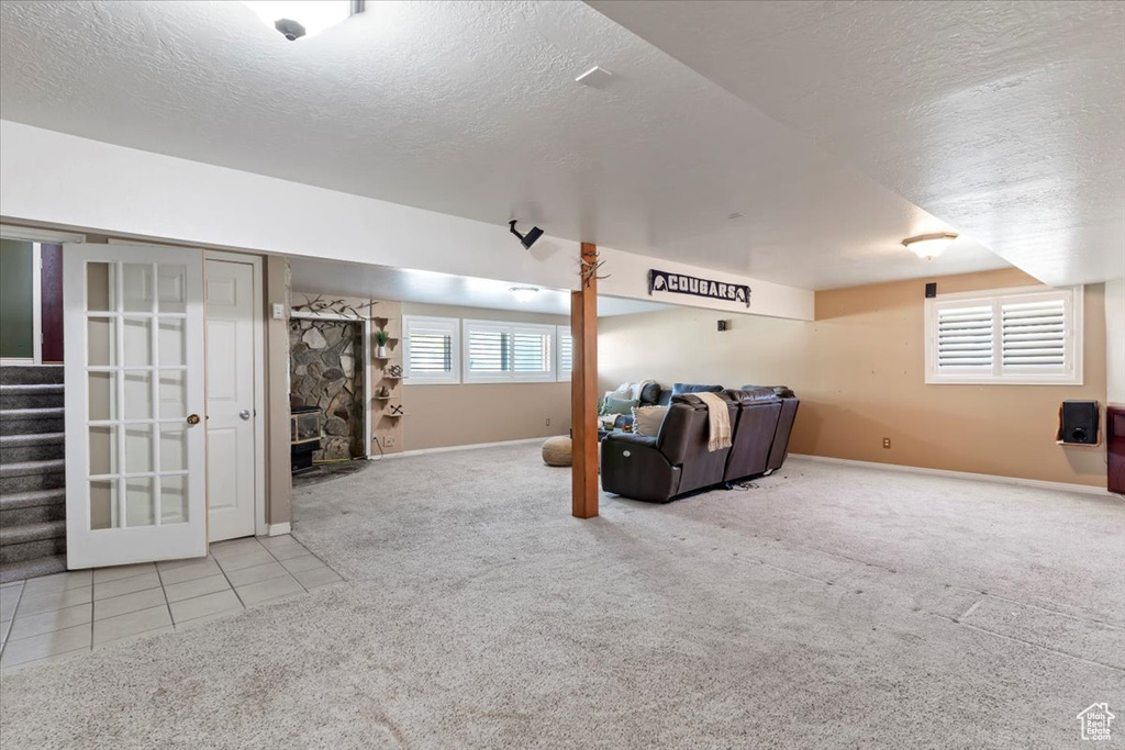 Carpeted living area with a textured ceiling, stairway, baseboards, and tile patterned flooring
