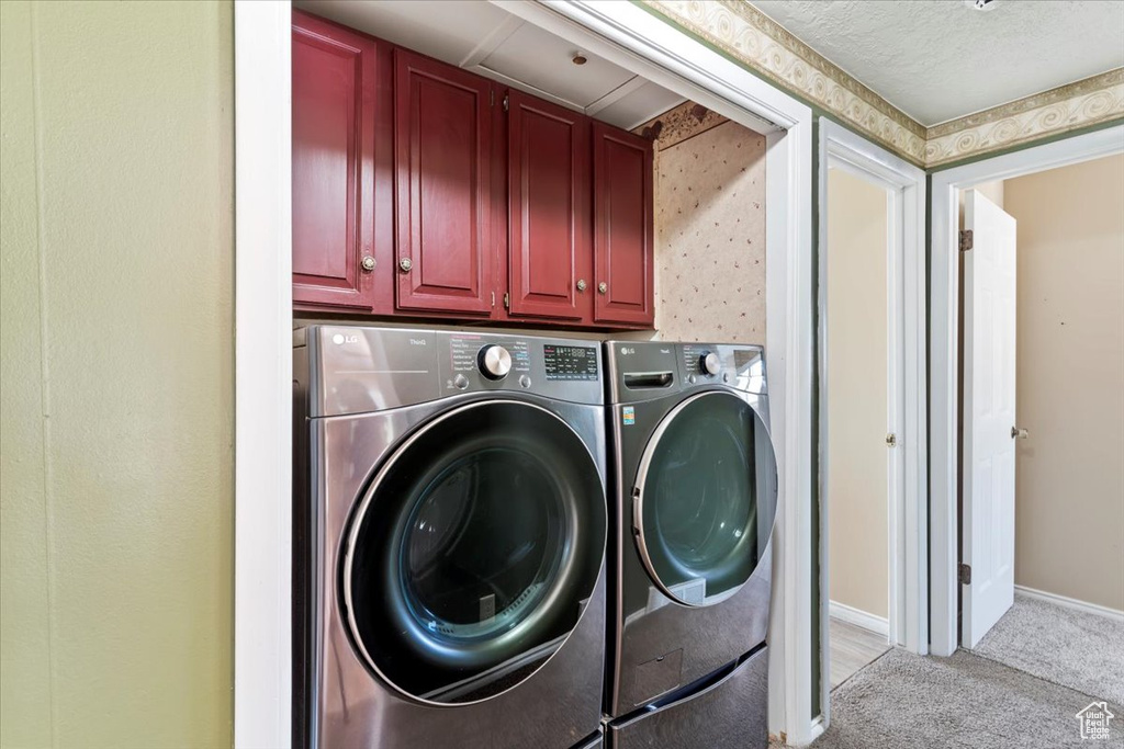 Washroom featuring independent washer and dryer, cabinet space, light carpet, and baseboards