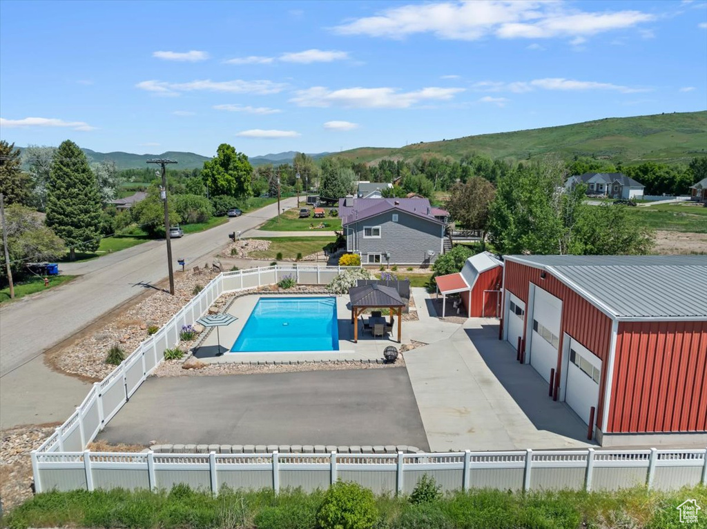 View of swimming pool with a mountain view, a fenced backyard, and an outdoor structure