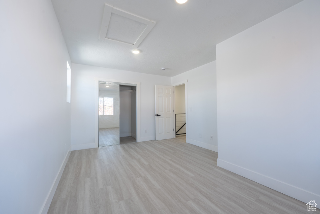 Empty room featuring light wood finished floors, baseboards, and attic access