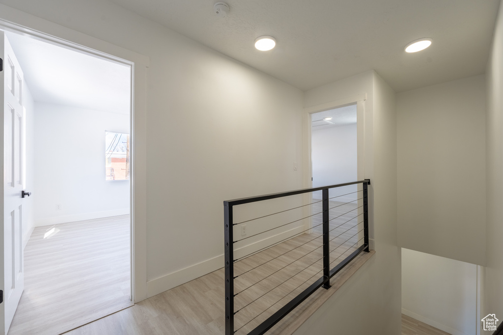 Hall with light wood finished floors, baseboards, and an upstairs landing