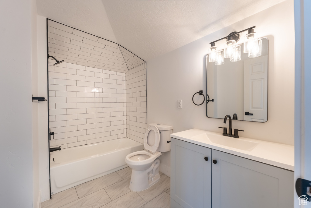 Full bathroom with toilet, lofted ceiling, vanity, shower / bath combination, and a textured ceiling