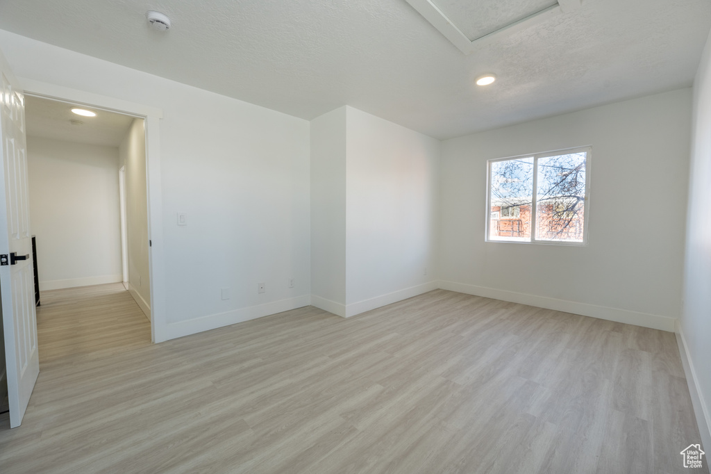 Spare room featuring recessed lighting, light wood-style floors, a smoke detector, baseboards, and attic access