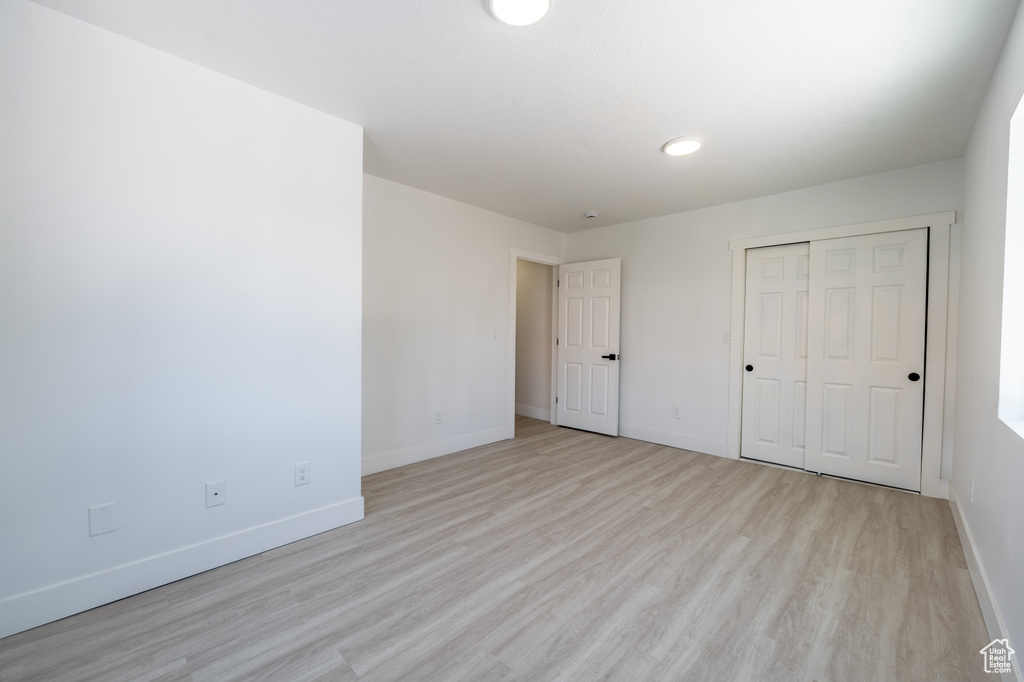Unfurnished bedroom featuring baseboards, light wood-type flooring, and a closet