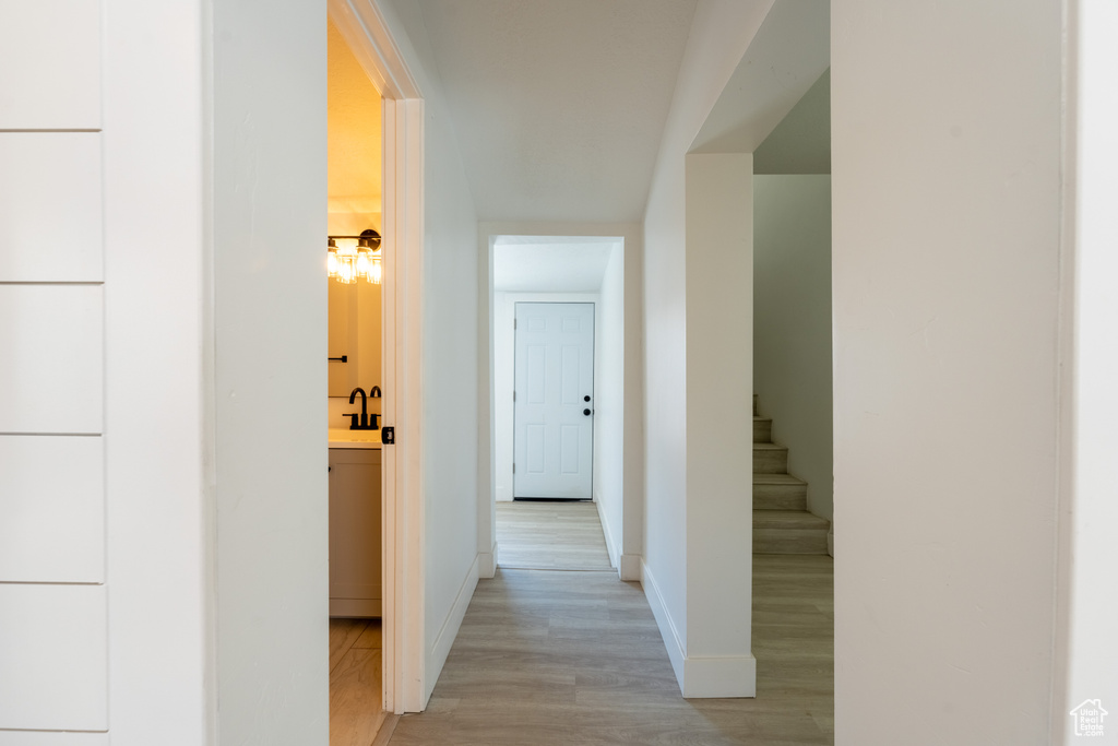 Hallway with light wood finished floors, baseboards, and stairway