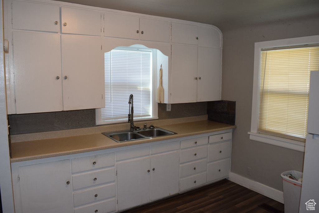 Kitchen featuring a sink, white cabinetry, dark wood finished floors, light countertops, and baseboards