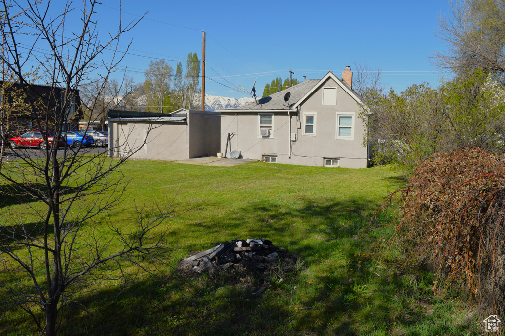 Back of property with a chimney, a yard, and roof with shingles