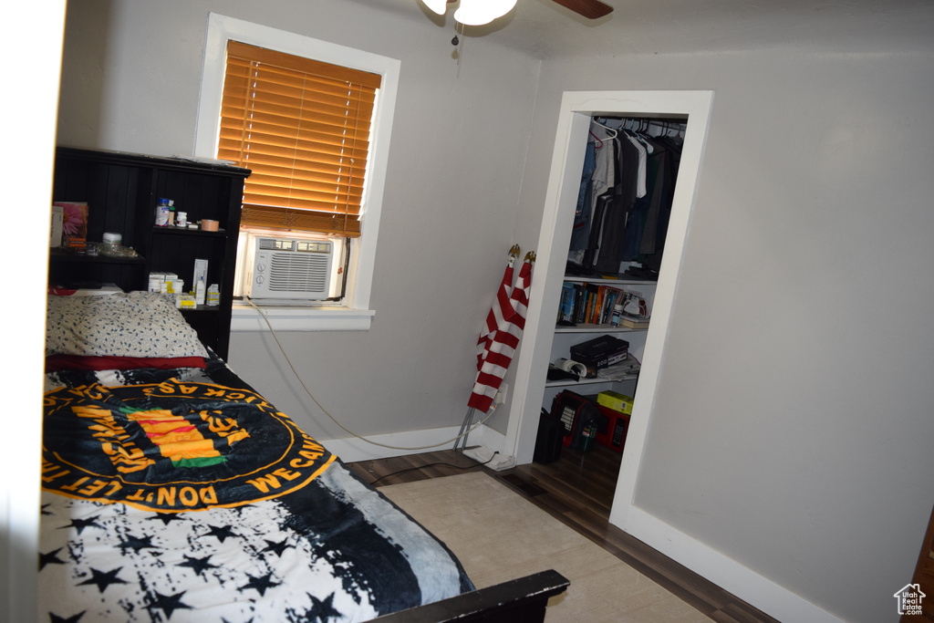 Bedroom with wood finished floors, baseboards, a ceiling fan, and cooling unit