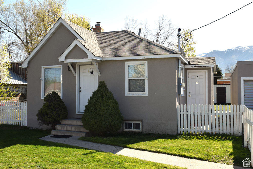 View of front of house with a shingled roof, stucco siding, a chimney, and a mountain view