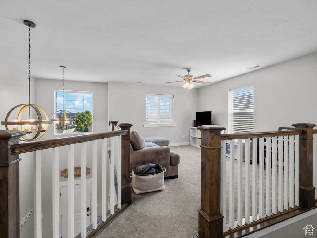 Carpeted living area with a chandelier, healthy amount of natural light, ceiling fan, and baseboards