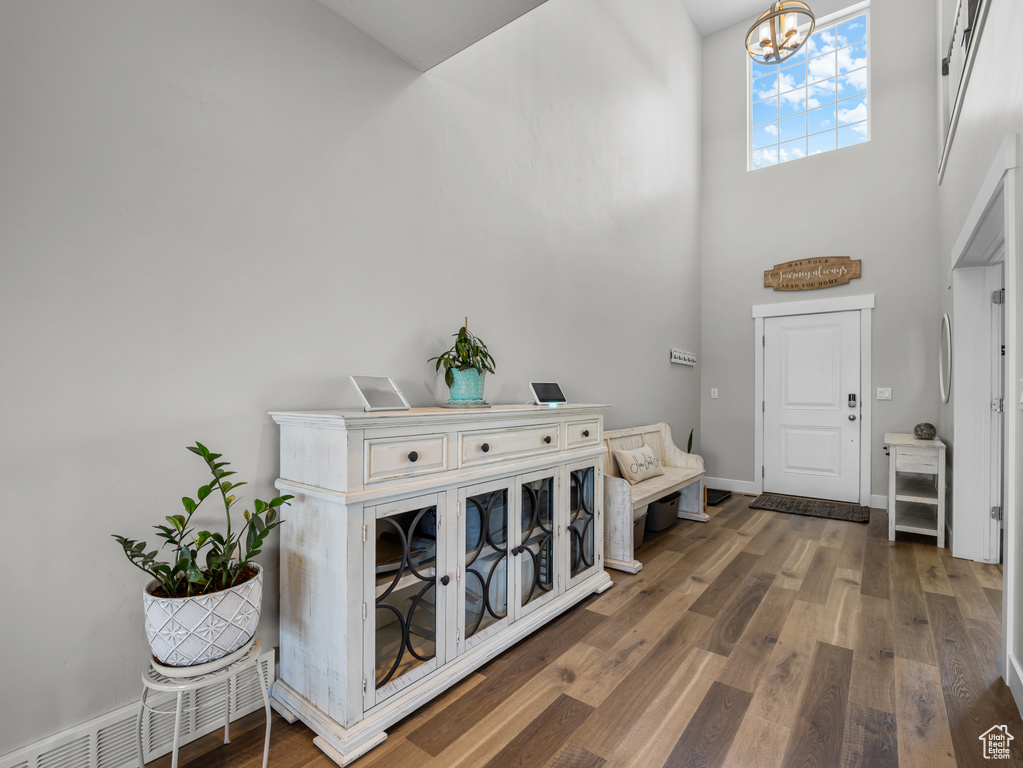 Entryway featuring a high ceiling, wood finished floors, a chandelier, and baseboards