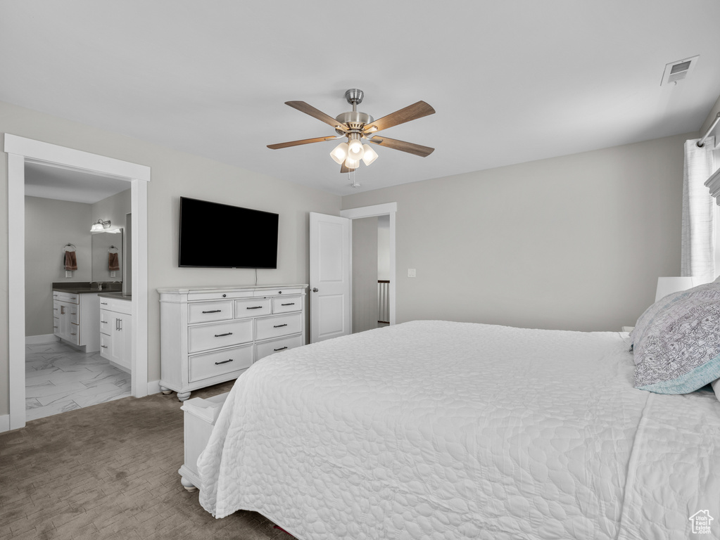 Bedroom with light marble finish flooring, baseboards, ensuite bath, and ceiling fan