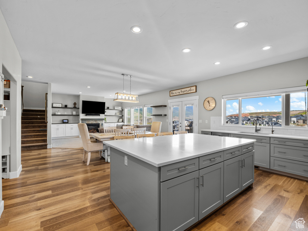 Kitchen with gray cabinets, a sink, light countertops, a center island, and recessed lighting