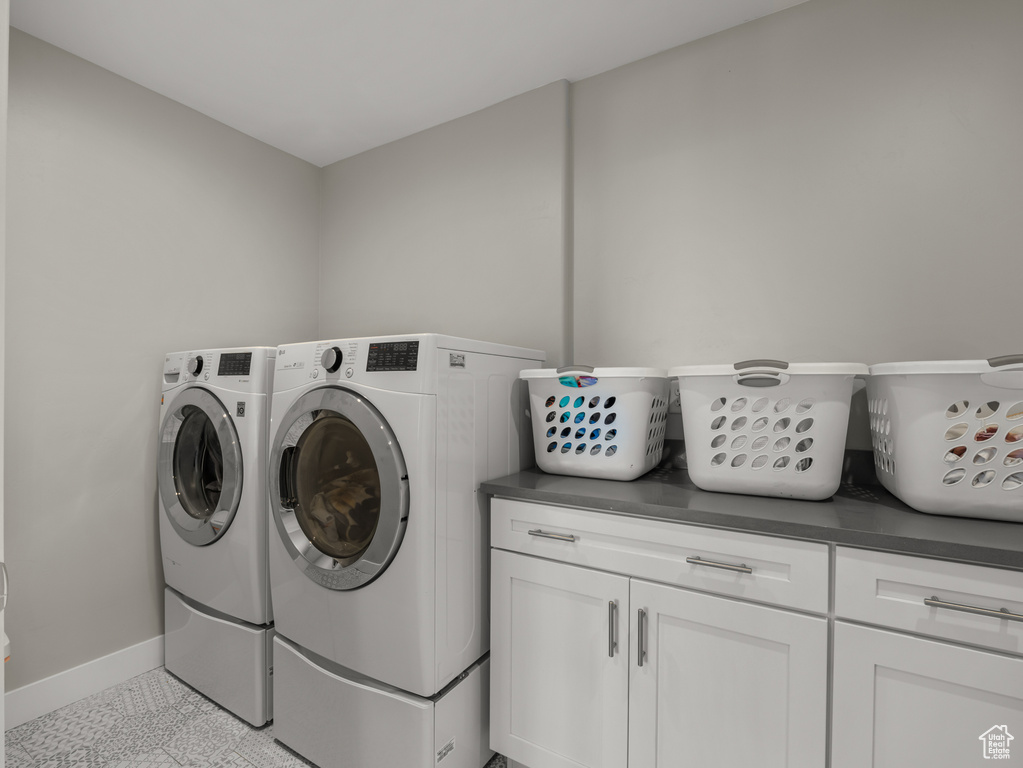 Laundry room featuring independent washer and dryer, baseboards, and cabinet space