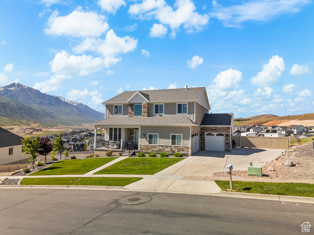 View of front of home featuring stone siding, concrete driveway, covered porch, a garage, and a mountain view