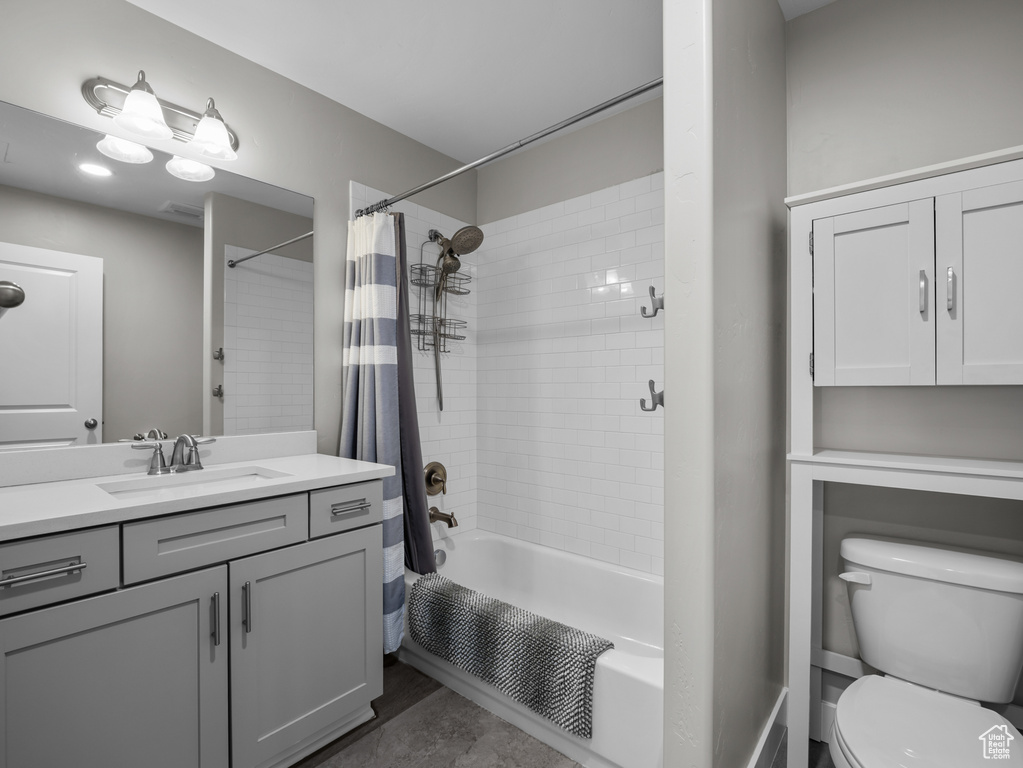 Bathroom with shower / bath combo with shower curtain, vanity, and toilet