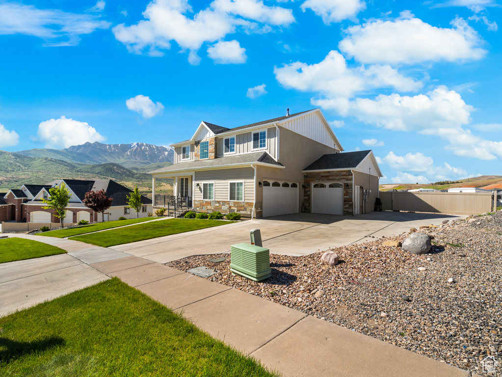 View of front of home with stone siding, a mountain view, driveway, and an attached garage