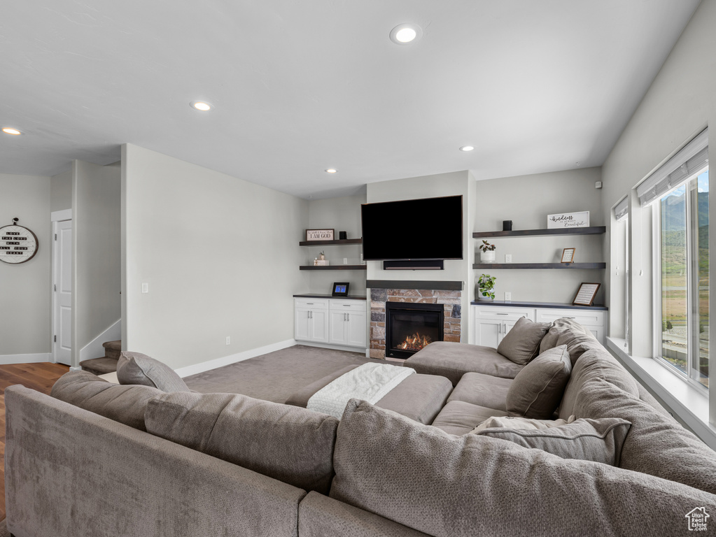 Living area with recessed lighting, baseboards, a stone fireplace, stairs, and a dry bar