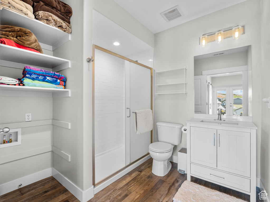 Bathroom featuring wood finished floors, a shower stall, toilet, vanity, and recessed lighting