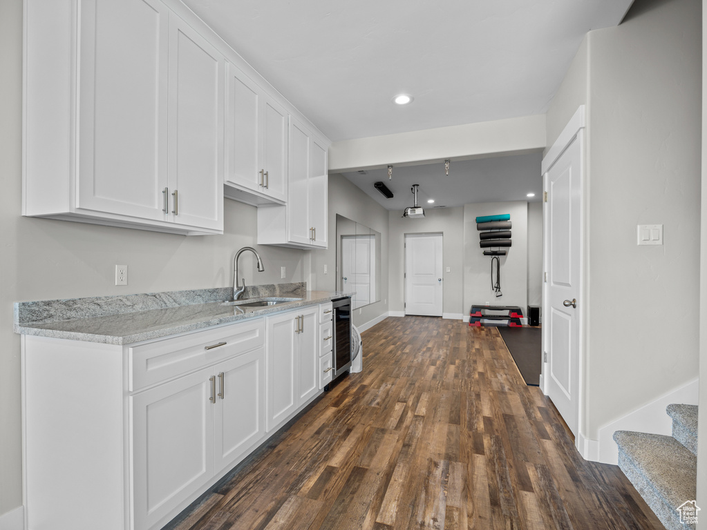 Kitchen featuring wine cooler, white cabinetry, a sink, dark wood finished floors, and baseboards