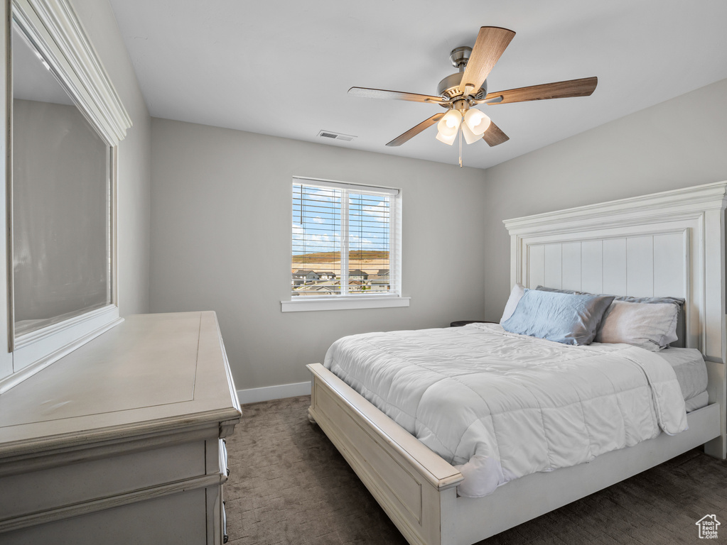Bedroom featuring baseboards, dark carpet, and ceiling fan
