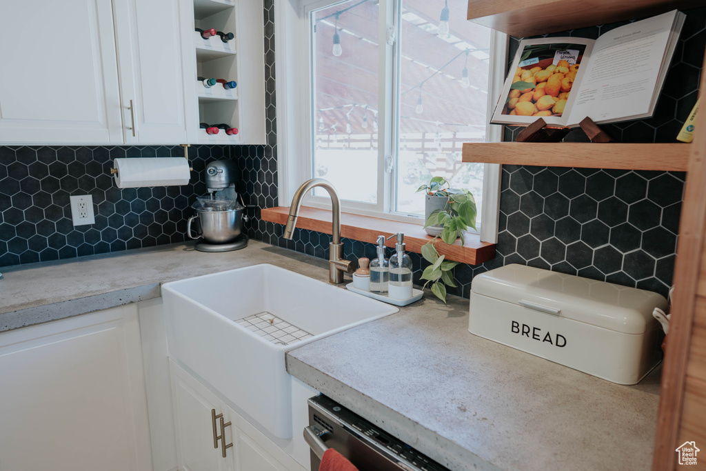 Kitchen featuring open shelves, a sink, white cabinets, and tasteful backsplash