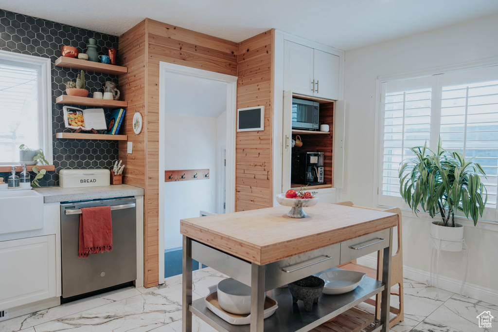 Kitchen featuring appliances with stainless steel finishes, plenty of natural light, light marble finish flooring, and open shelves