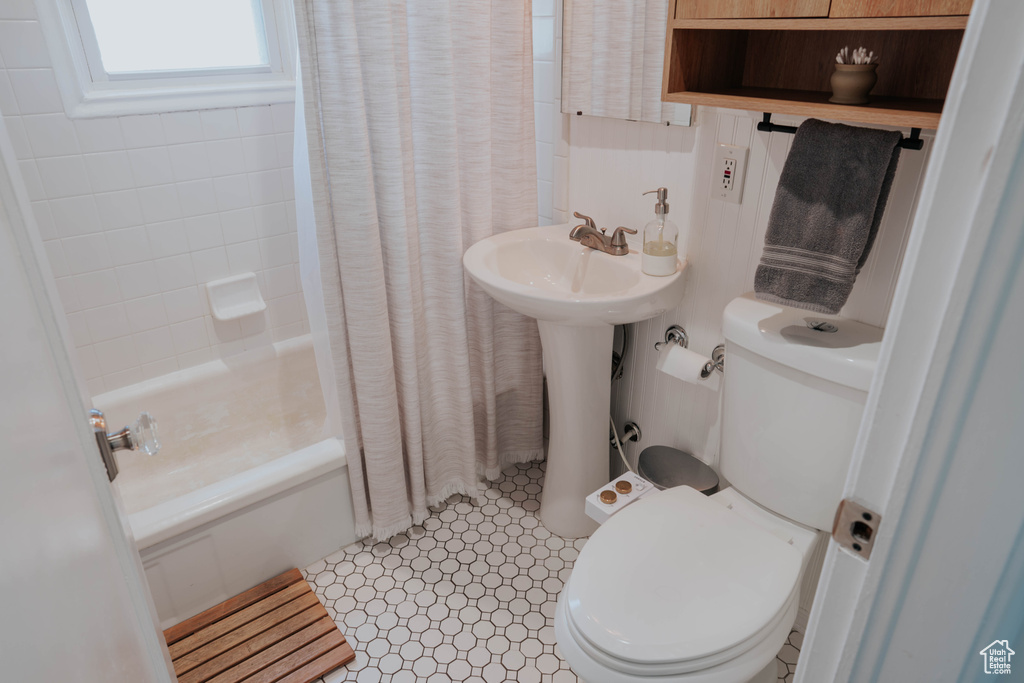 Full bathroom featuring toilet, shower / tub combo with curtain, and a sink