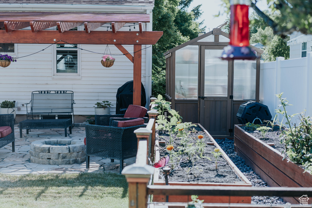 View of patio featuring an exterior structure, an outbuilding, a garden, a fire pit, and a grill