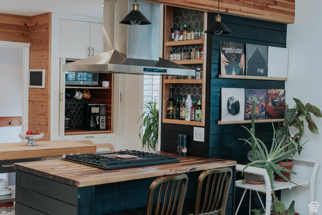 Kitchen with wooden counters, island range hood, gas cooktop, and white cabinetry