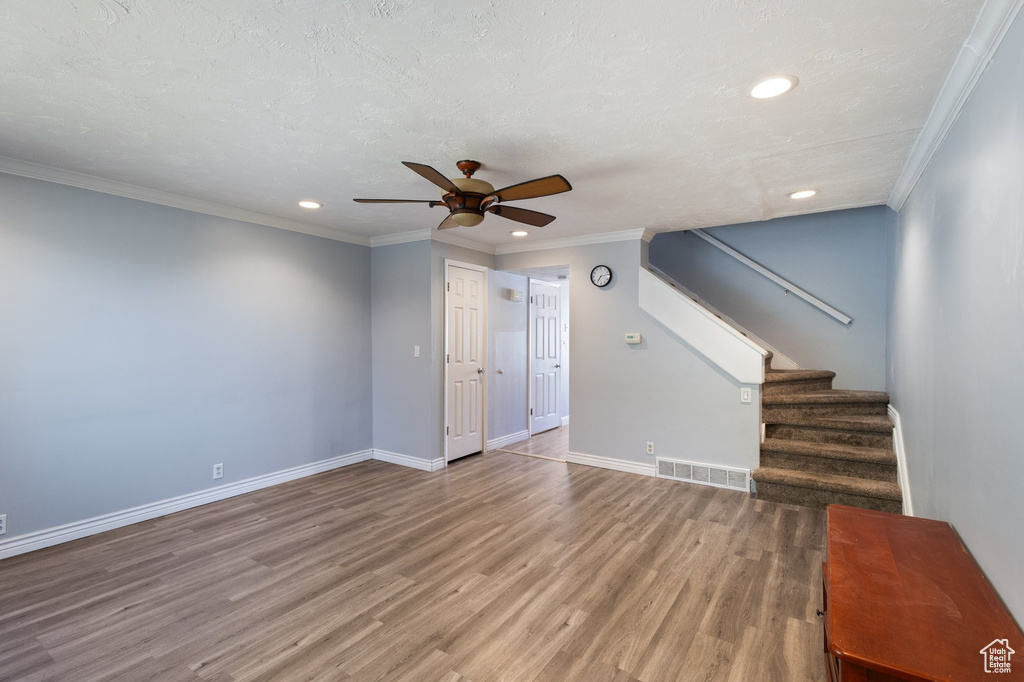 Unfurnished living room featuring recessed lighting, a ceiling fan, wood finished floors, stairs, and ornamental molding