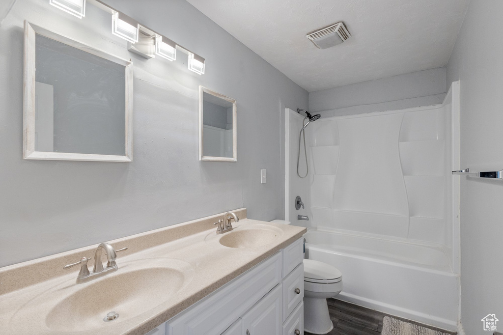 Bathroom featuring double vanity, washtub / shower combination, and wood finished floors