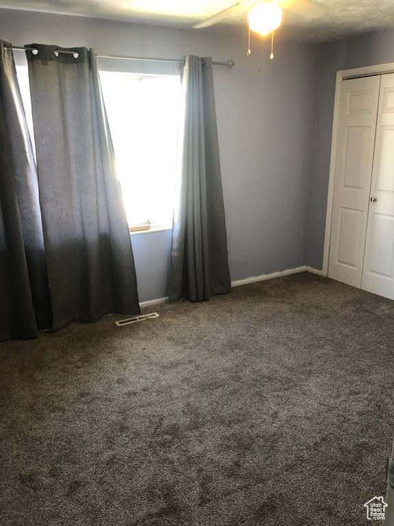 Carpeted spare room with baseboards and ceiling fan