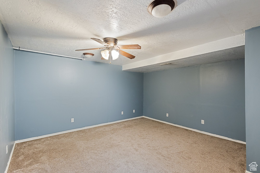 Carpeted empty room with ceiling fan and a textured ceiling